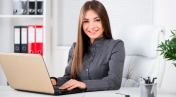 Germany, Bavaria, Munich, Businesswoman using computer in office, smiling, portrait